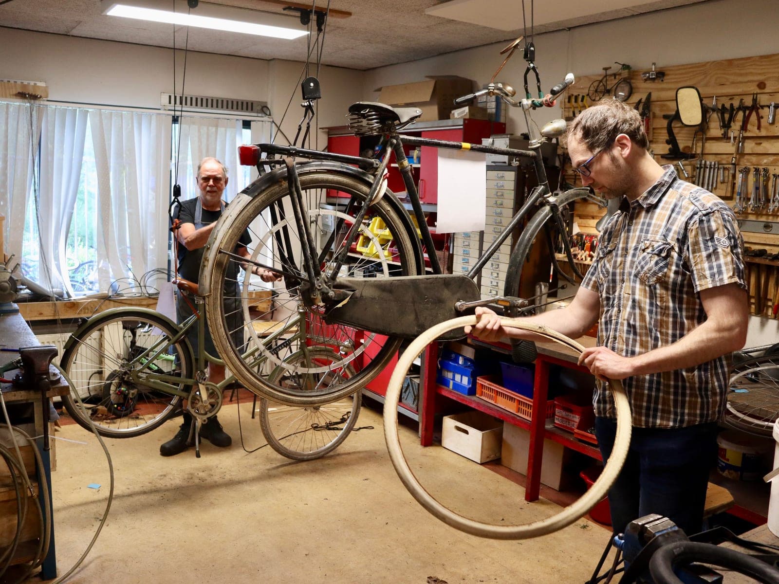 Een leermeester en een gezel werken samen aan een fiets